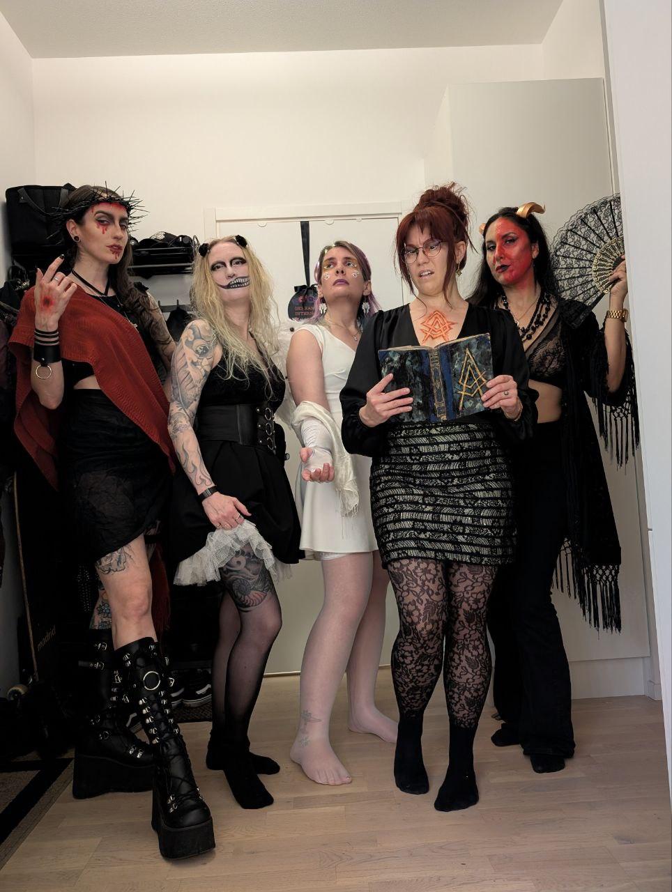 Ash in white as an angel surrounded by four other women in black as the antichrist, a creepy doll, a posessed librarian, and a demon.