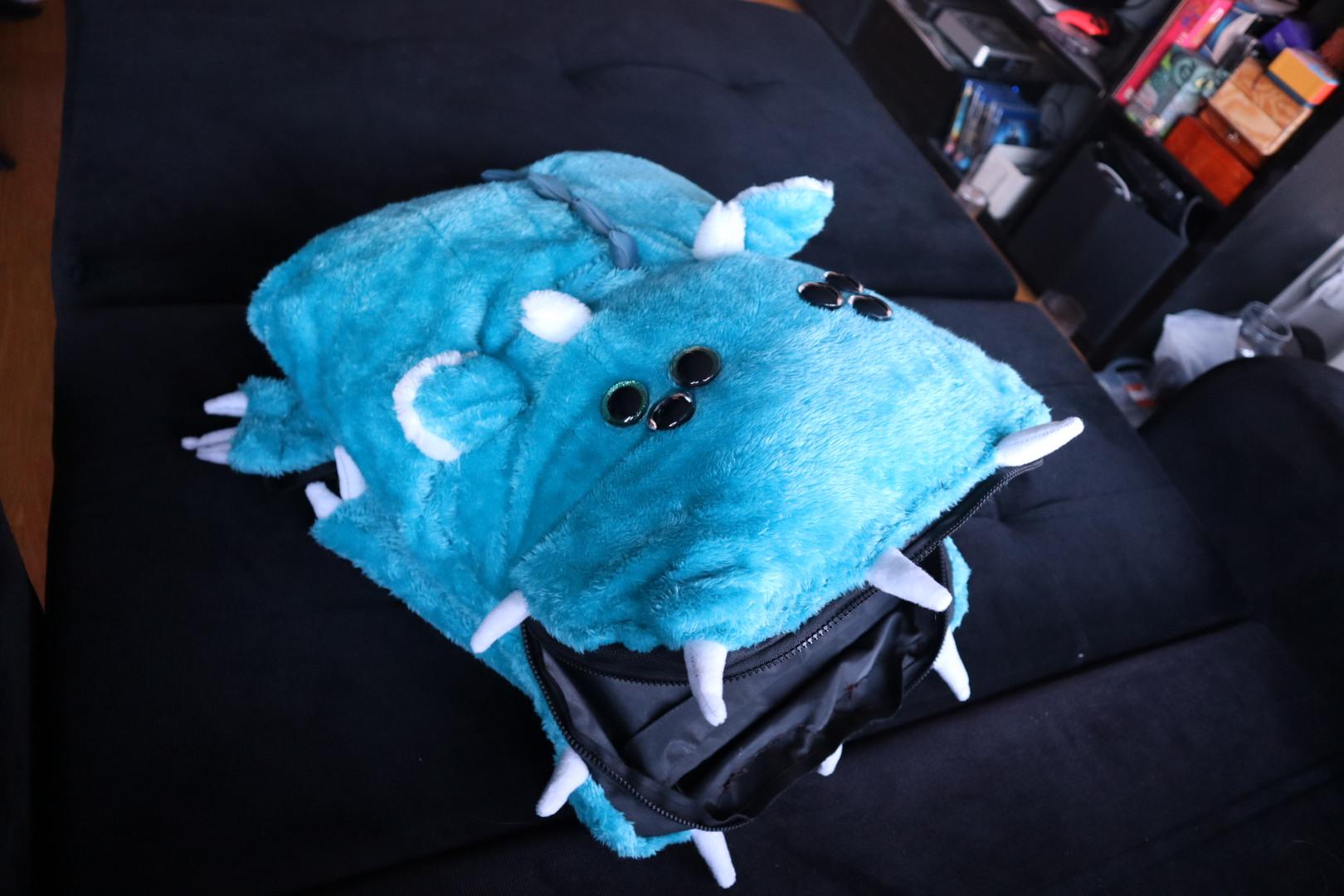 Bright blue cyan plush monster backpack with its tooth lined zipper mouth open