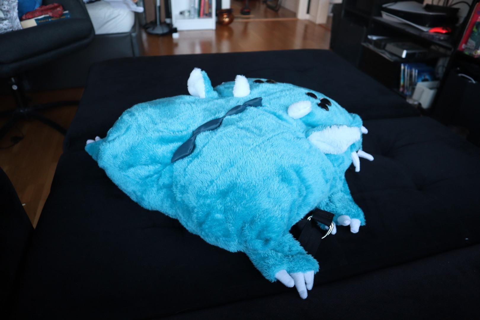 Bright blue cyan plush monster backpack from behind showing of back ridge, clawed limbs attached to straps, and ass cheeks