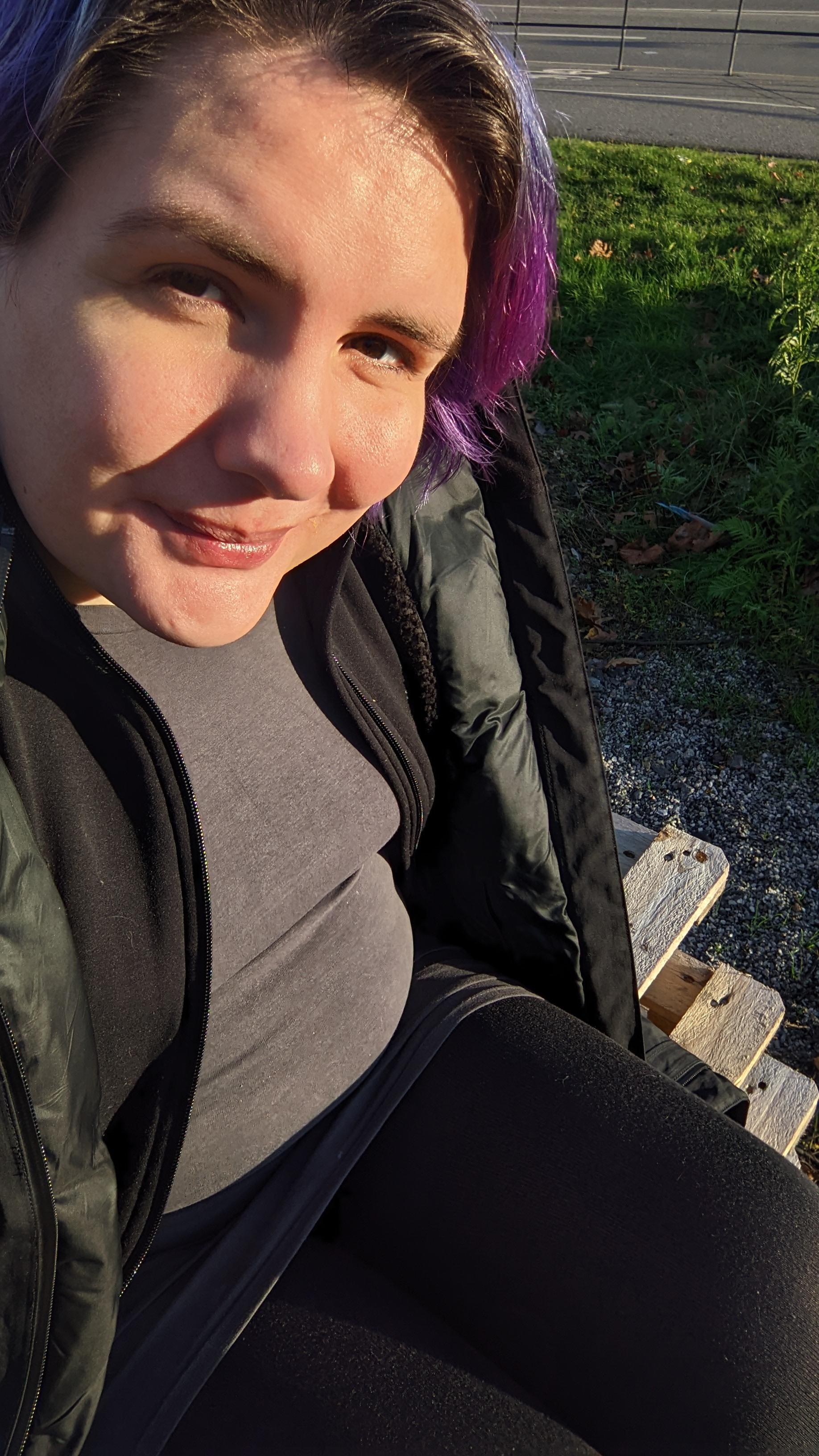 Ash sitting on some wooden pallets next to the road, in the sun