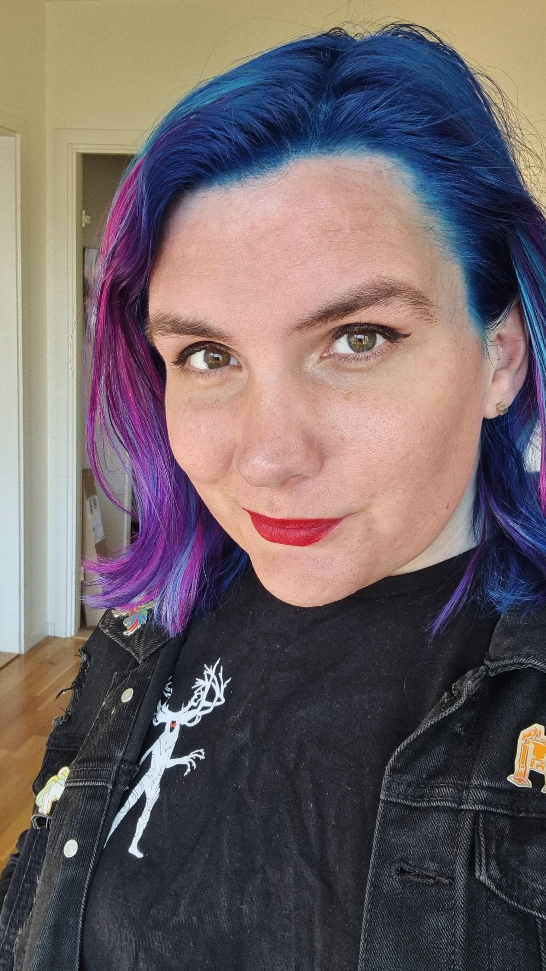 Ash has shoulder length hair coloured blue with violet streaks like a distant galaxy far out in space