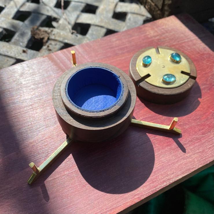 cylindrical ring box made of brass, zircote wood, with aquamarines on top. Photo of inside