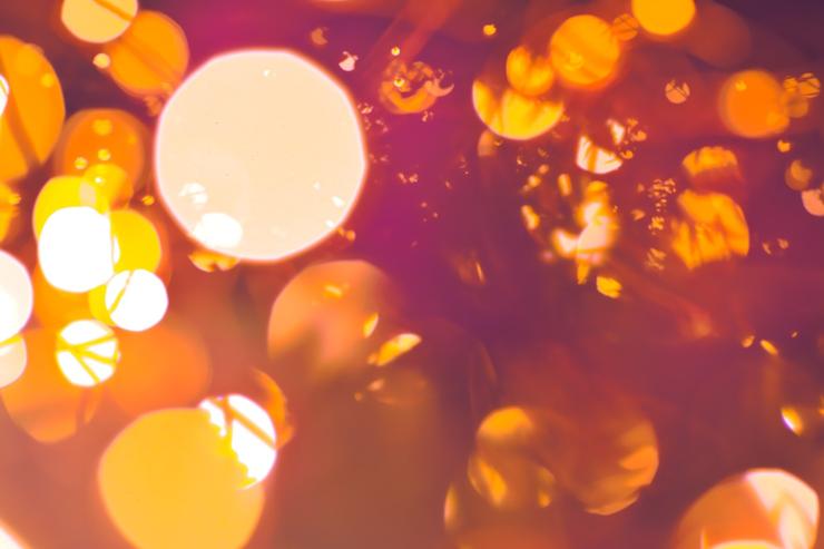 An abstract photograph, bokeh circles and soft indistinct shapes fill the frame in warm yellows and pinks.